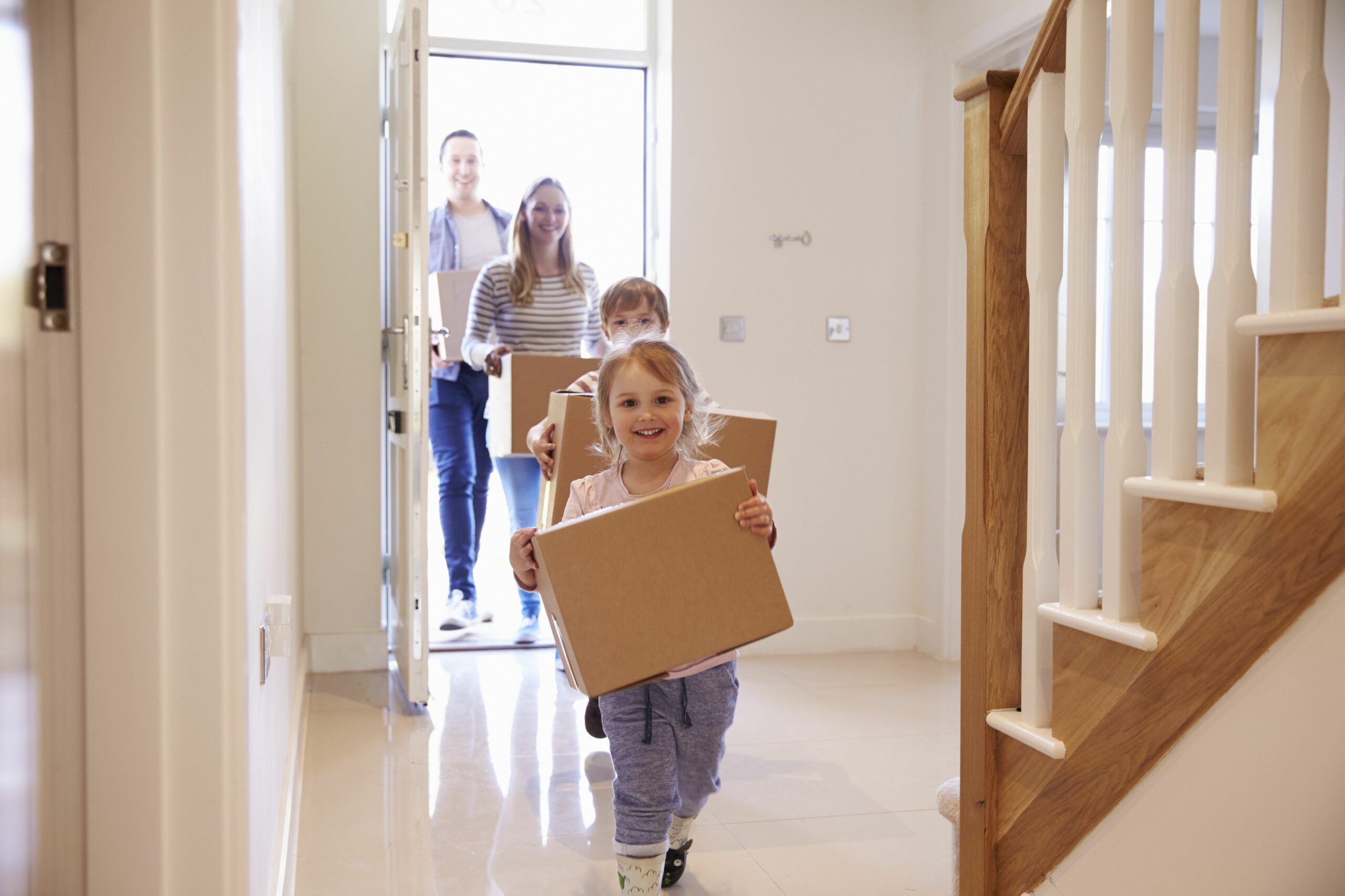 Using a solicitor estate agent when moving home. Family carrying boxes into new home on moving day.