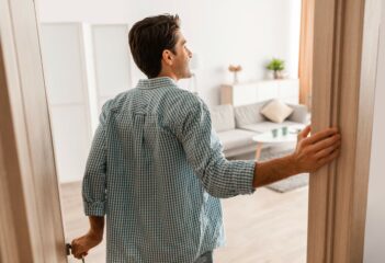 Top tips for viewing a property. Rear back view of excited young man walking in his apartment, entering new home, happy young guy standing in doorway of modern flat.