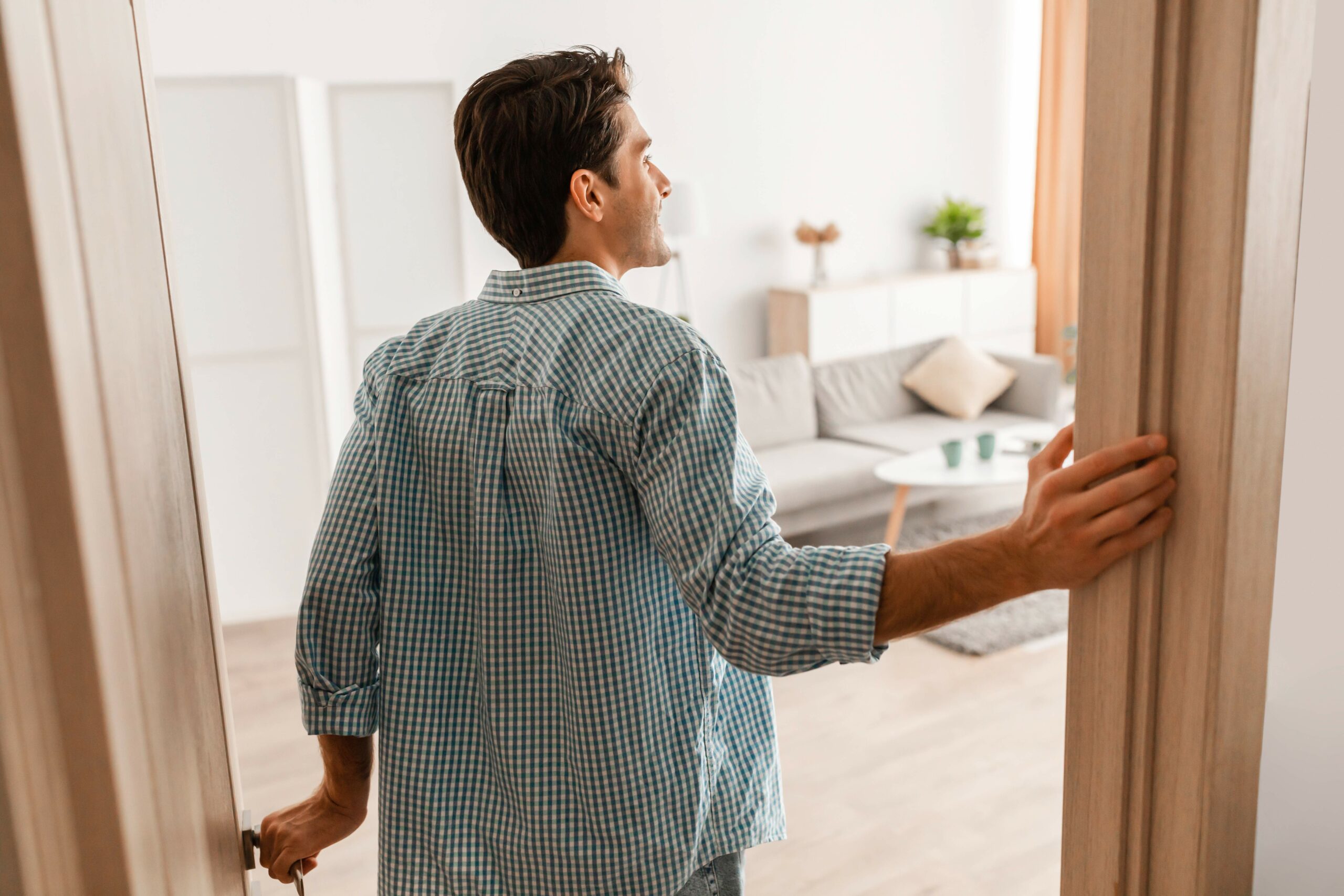 Top tips for viewing a property. Rear back view of excited young man walking in his apartment, entering new home, happy young guy standing in doorway of modern flat.